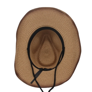 Internal detail of a dark khaki woven straw cowboy hat with a black windproof chin strap