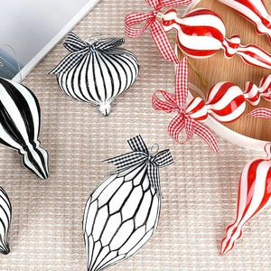 Christmas ornaments set with red, black, and white patterns and bow ties on beige fabric