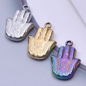 Vue macro des pendentifs Main de Fatma en acier doré, argenté et arc-en-ciel