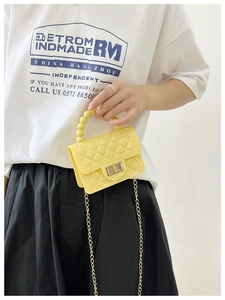 Close-up of yellow quilted jelly bag with pearl handle and metal chain shoulder strap