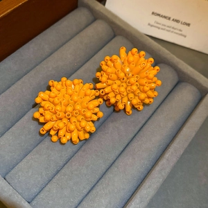 Macro detail of orange floral cluster stud earrings in a velvet jewelry box