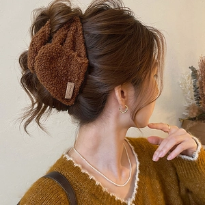 Detail der flauschigen braunen Haarklammer mit Sweet-Label am Haar des Models