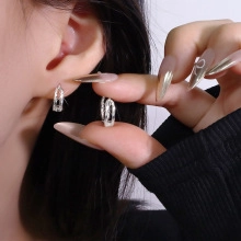 Close-up of silver huggie hoop earrings with textured hammered finish on a model