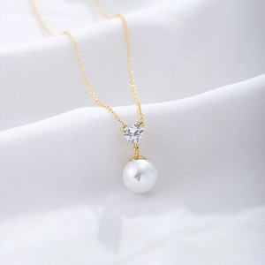 Macro shot of gold S925 silver necklace with heart zircon and white pearl pendant