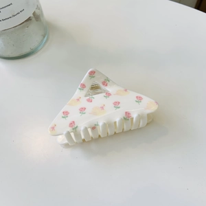 Detail of white triangle hair claw clip with pink rose and yellow duck patterns