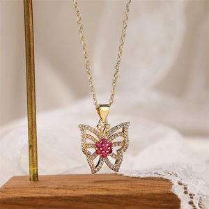 Macro detail of gold butterfly pendant with red and clear crystals on a metal stand