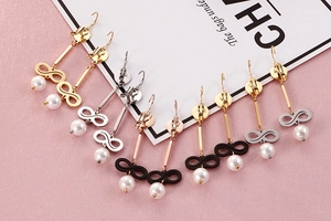 Detail view of infinity symbol pearl earrings in five metallic finishes on a soft background