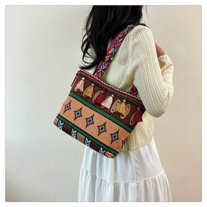 Ethnic style woven shoulder bag with geometric patterns and fringe tassels on a model