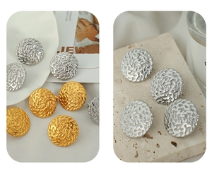 Detail of round woven texture relief earrings in gold and silver finish