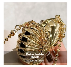 Detail of detachable gold lobster clasp and spherical metal chain on the shell clutch
