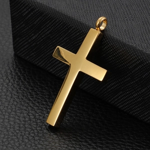 Gros plan d'un pendentif croix minimaliste en acier inoxydable doré sur surface noire