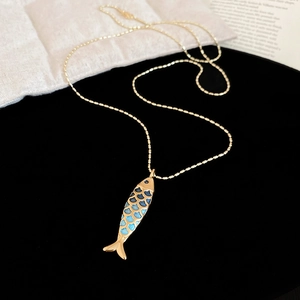 Detailed close-up of a golden fish pendant with blue gradient enamel on a bead chain