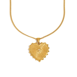 Detail of 18K gold plated heart pendant with sunburst pattern and center diamond inlay