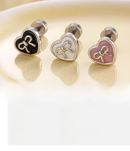 Macro view of heart-shaped enamel studs with bow design in black, white, and pink