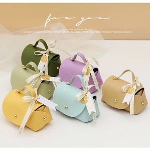 Detailed view of colorful handbag-style wedding favors with Love Is Eternal ribbons