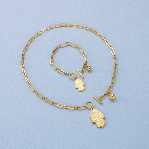 Detail of golden Hamsa hand pendant and paperclip chain set with elegant OT clasp