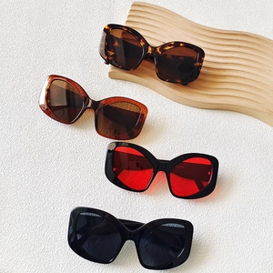 Close-up of stylish cat-eye sunglasses with thick frames and textured wooden display