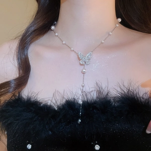 Dettaglio della collana con pendente a farfalla, zirconi brillanti e perle bianche eleganti