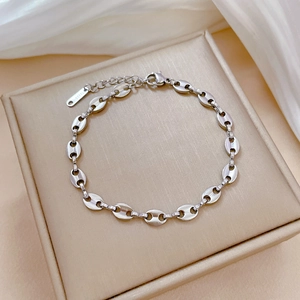 Macro view of silver stainless steel coffee bean link bracelet on soft silk background