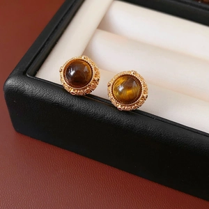 Detaillierte Makroansicht antiker Gold-Ohrstecker mit runden Tigerauge-Steineinlagen