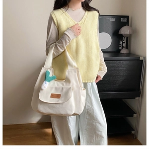 White canvas tote bag with cactus charm and front pocket detail in a home setting