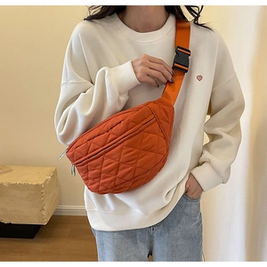 Detail of orange quilted nylon crossbody bag featuring wide strap and secure buckle closure