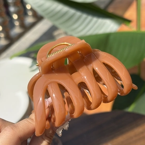 Elegant amber pumpkin-shaped hair claw clip with golden spring in natural light