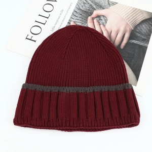 Detail of soft ribbed knit texture on a burgundy winter beanie with a grey stripe accent