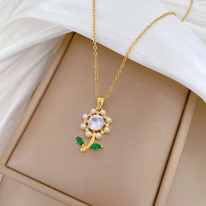 Elegant gold flower necklace with white pearls, green leaves and a sparkling zircon center