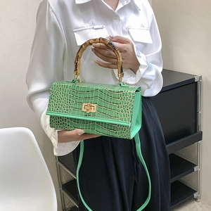 Detail of green crocodile embossed PU leather handbag featuring a bamboo handle and strap