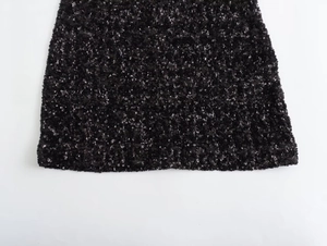 Close-up of black sequin fabric detail showing the craftsmanship of the dress hemline