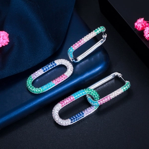 Macro view of long oval buckle earrings with rainbow zircons and silver-plated finish