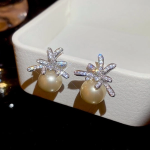 Macro shot of silver pearl earrings with zircon floral accents on a jewelry box