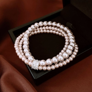 Gros plan détaillé d'un bracelet de perles roses à trois rangs avec fermoir en cristal