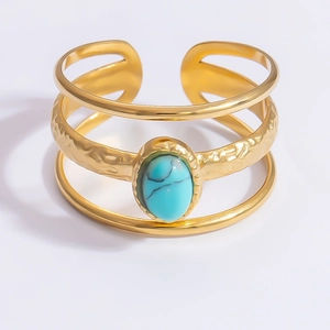 Detail of layered gold cuff bracelet featuring natural turquoise stone and hammered texture
