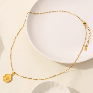 Macro detail of golden stainless steel round pendant with moon engraving on texture