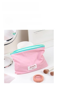 Detail of pink macabre zipper pouch with teal zipper and brand tag on vanity table