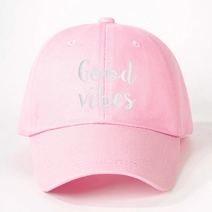 Close-up detail of Good Vibes white embroidery on a light pink cotton baseball cap