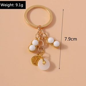 Detail of gold metal keychain with jade-like bead, peanut charm and Fu character coin