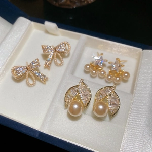 Detailed macro of gold plated star and pearl earrings with cubic zirconia on velvet