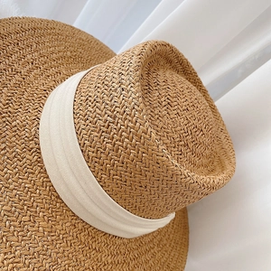 Detail of hand-woven straw hat with intricate texture and decorative beige ribbon