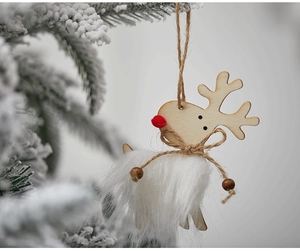 Macro detail of white wool elk ornament with wooden base hanging on a snowy Christmas tree