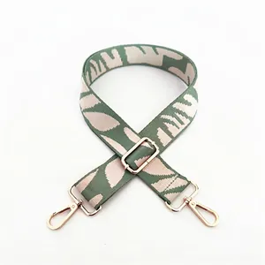 Adjustable woven handbag strap with grey-green leaf pattern and gold metal hooks
