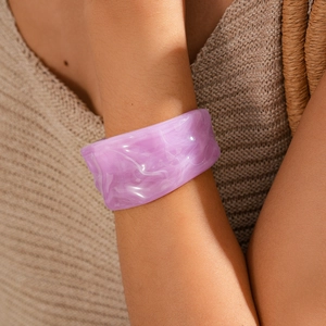 Close-up of wide purple acrylic cuff bracelet with white marble texture on a female wrist