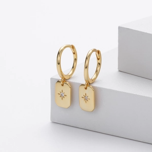 Detailed close-up of golden S925 sterling silver hoop earrings with star pendant and zircon