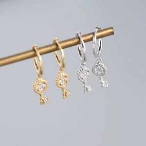 Detail view of silver and gold key earrings with sparkling zircon stones and click closure