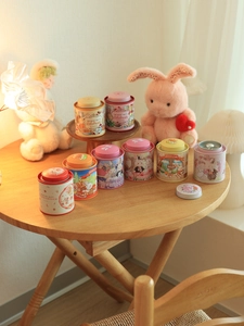 Close-up of pastel tin tea canisters with bunny illustrations on a wooden table