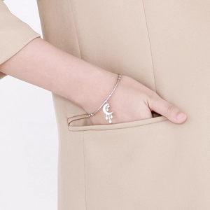 Silver stainless steel moon and star bangle shown on a model wearing a khaki blazer