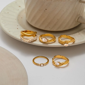 Elegant 5-piece gold pearl ring set with twisted bands and crystal accents on ceramic