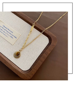 Close-up of a gold necklace with oval tiger eye stone pendant on a wooden tray